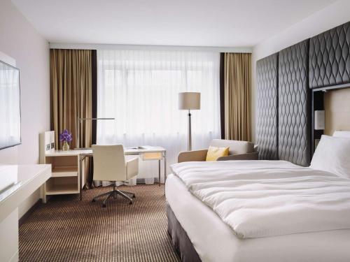 a hotel room with a bed and a desk at Pullman Berlin Schweizerhof in Berlin