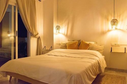 ein Schlafzimmer mit einem großen weißen Bett mit zwei Leuchten in der Unterkunft Apartment with sea-view in Golf Bonalba Alicante in Mutxamel