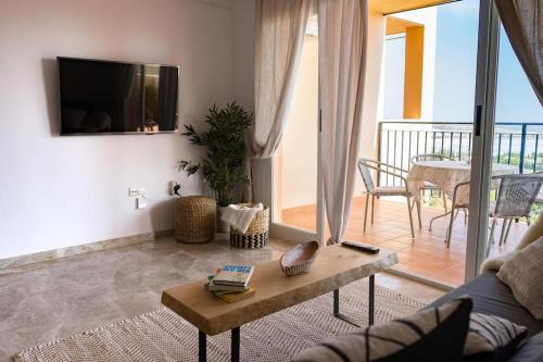 ein Wohnzimmer mit einem Sofa, einem TV und einem Tisch in der Unterkunft Apartment with sea-view in Golf Bonalba Alicante in Mutxamel