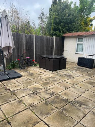 a patio with an umbrella and a table and a fence at Affordable Room to Rent for Short Stay in Abbey Wood