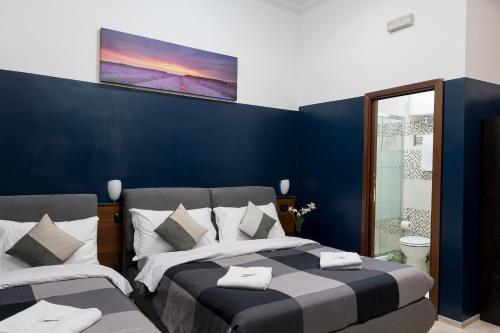 a bedroom with two beds and a blue wall at STELLA GUEST HOUSE O AFFITTACAMERE in Rome