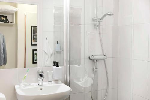 a white bathroom with a shower and a sink at Scandic Sjöfartshotellet in Stockholm