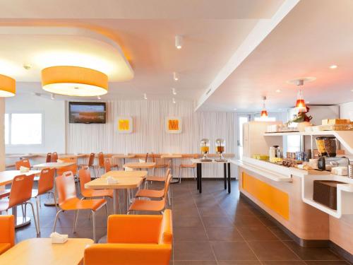 ein Restaurant mit orangefarbenen Stühlen und Tischen sowie eine Bar in der Unterkunft Ibis budget Wien Messe in Wien