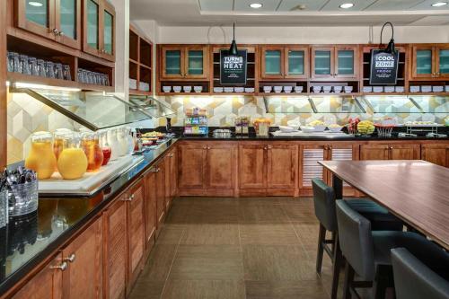 uma grande cozinha com armários de madeira e um bar com bebidas em Hyatt Place Detroit/Auburn Hills em Auburn Hills