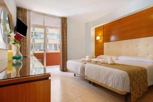 a hotel room with two beds and a tv at Apartamento Alta 507 in Puerto de la Cruz
