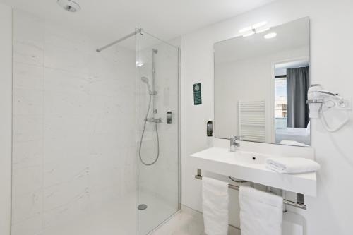 a white bathroom with a shower and a sink at All Suites Appart & Hotel Paris 13 Porte d'Italie in Paris