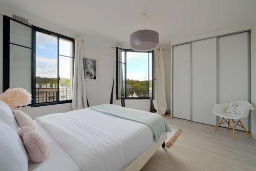 a bedroom with a large bed and large windows at Charmant Appartement au Cœur de Boulogne in Boulogne-Billancourt