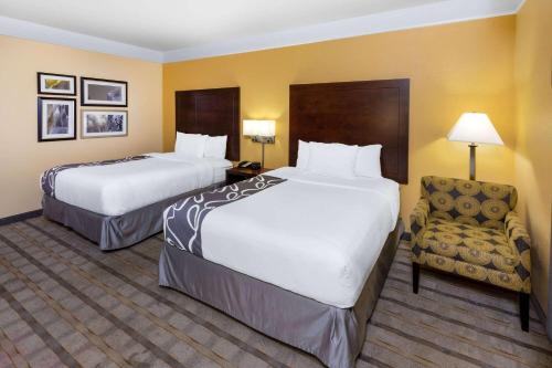a hotel room with two beds and a chair at La Quinta by Wyndham Houston NW Beltway8/WestRD in Houston