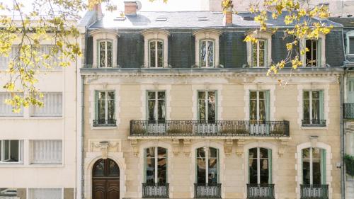 - un grand bâtiment avec un balcon sur le côté dans l'établissement Les Suites de L’Opéra, à Vichy