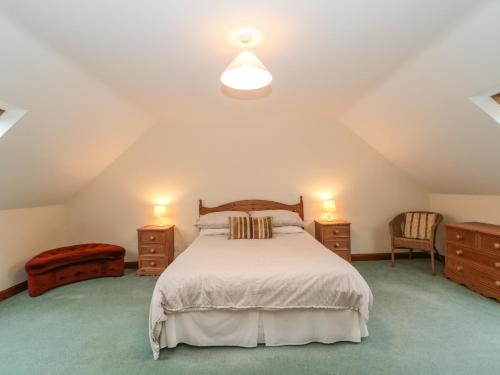 a bedroom with a bed and two dressers and two lamps at Cartshed Cottage in Weymouth