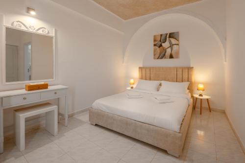 a bedroom with a bed and a desk and a mirror at Nevma Suites in Firostefani