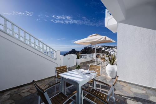 a table and chairs on a balcony with an umbrella at Nevma Suites in Firostefani