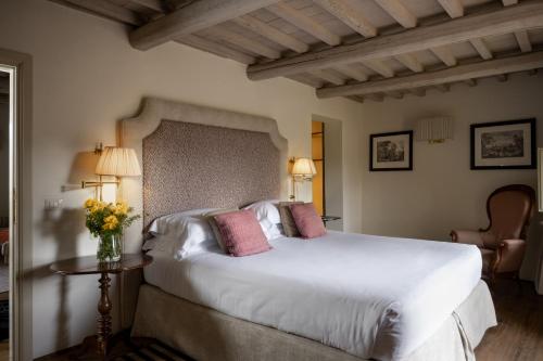 1 dormitorio con 1 cama blanca grande con almohadas rosas en Il Borro Relais & Châteaux, en San Giustino Valdarno