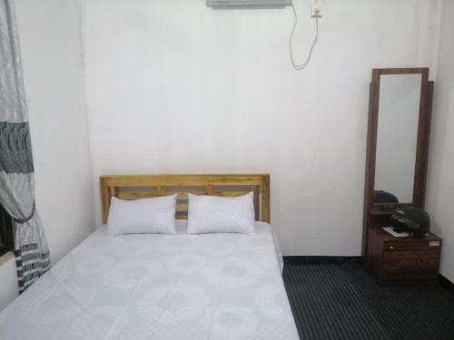 una camera con letto bianco e specchio di ZAHIRA Beach Place Kattankudy a Kattankudi