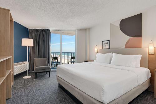 Spark by Hilton Ormond Beach Oceanfront في شاطئ أورموند: غرفه فندقيه بسرير وشرفه