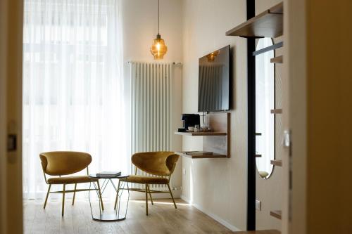 Pokój z 2 krzesłami, stołem i oknem w obiekcie Electric Rooms & Suites w Trydencie