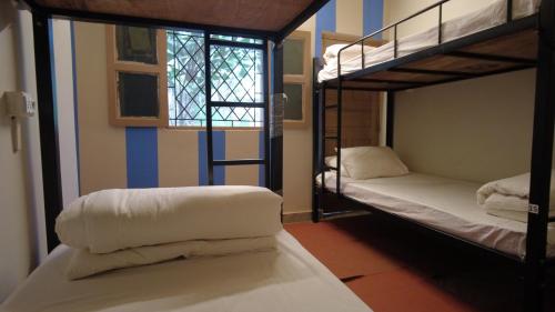 a room with two bunk beds and a window at The Peace Hostel - Arambol, Goa in Arambol