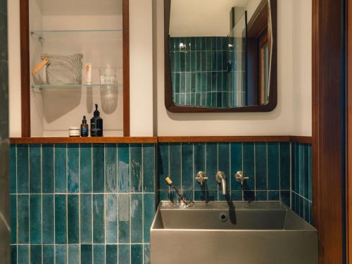 ein Bad mit einem Waschbecken und einem Spiegel in der Unterkunft The Hoxton Vienna in Wien