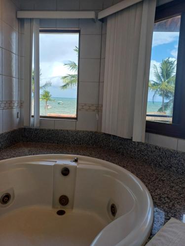 a bath tub in a bathroom with a view of the beach at Pousada Vivenda Oriente in São José da Coroa Grande