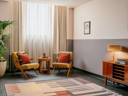 a room with two chairs and a table and a window at The Hoxton Vienna in Vienna