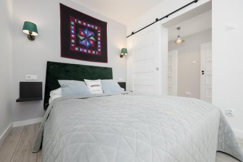 ein weißes Schlafzimmer mit einem großen Bett mit einem grünen Kopfteil in der Unterkunft Schillera Apartments Warsaw by Renters in Warschau
