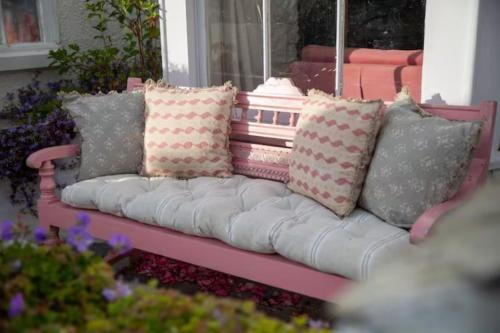 a pink couch with pillows sitting on a porch at Geranium Cottage in Port Isaac