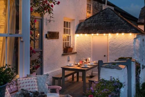 a patio with a table and lights on a house at Geranium Cottage in Port Isaac
