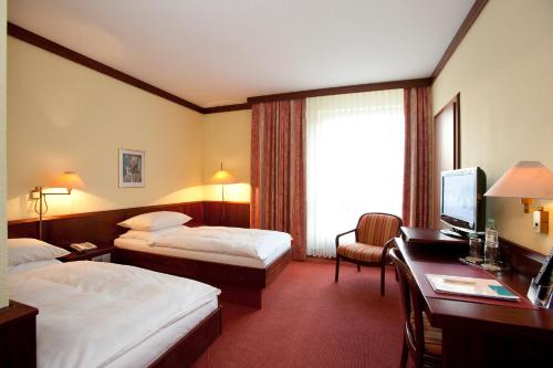 a hotel room with two beds and a desk at Leine Hotel in Pattensen