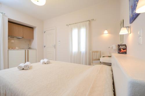 a white bedroom with a bed with towels on it at Irini Studios in Agia Anna Naxos