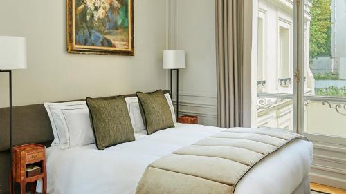 a white bed in a room with a window at Hôtel Lancaster Paris Champs-Elysées in Paris