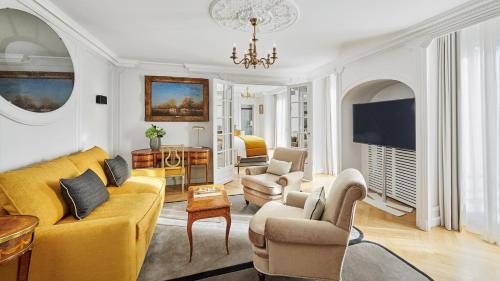 فندق لانكاستر باريس شانزليزيه في باريس: غرفة معيشة مع أريكة صفراء وكراسي