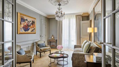 a living room with a couch and chairs and a chandelier at Hôtel Lancaster Paris Champs-Elysées in Paris