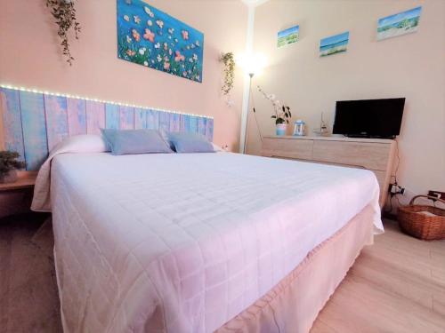 ein Schlafzimmer mit einem großen weißen Bett und einem TV in der Unterkunft Grazioso monolocale in Sardegna in Marina di Sorso