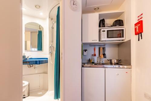 a small kitchen with white cabinets and a microwave at Studio Flat Farringdon in London