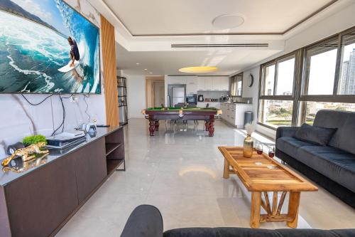 a living room with a couch and a pool table at פנטהאוז שמיים - דירות יוקרתיות על הים עם ממד,גקוזי פרטי, בריכה ונוף פנורמי לאוקיינוס in Netanya