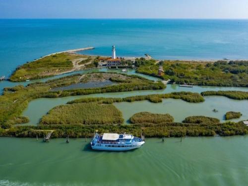 an island with a boat in the water with a lighthouse at Charming sea front view apartment-Beahost Rentals in Rosolina Mare