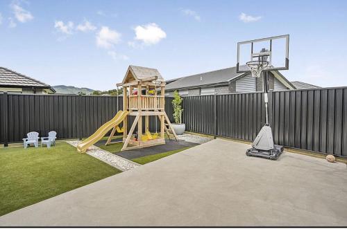 un patio trasero con un aro de baloncesto y un parque infantil en Private Ensuite with Spa in Upper Hutt, en Upper Hutt