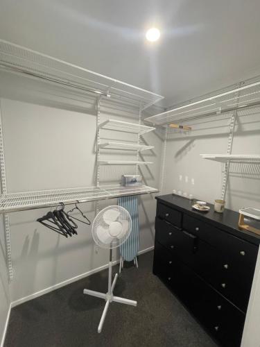 a kitchen with white shelves and a table and a desk at Private Ensuite with Spa in Upper Hutt in Upper Hutt