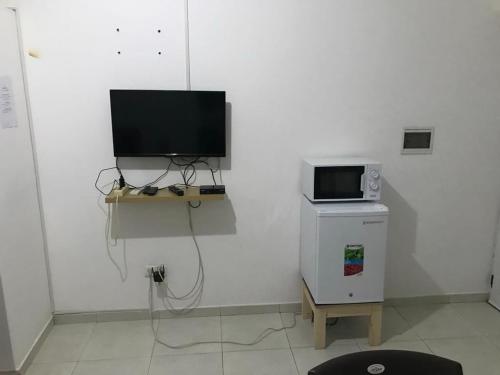 a white room with a television and a microwave at 2SB Hospedagem in Praia