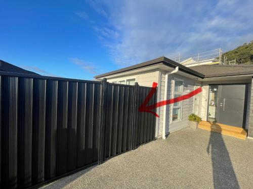 a house with a black fence with a red arrow at Private Ensuite with Spa in Upper Hutt in Upper Hutt