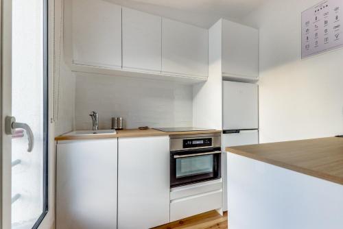 une cuisine blanche avec des armoires blanches et un évier dans l'établissement L'étincelle - Lumineux - Vue Tour Eiffel - BM, à Paris