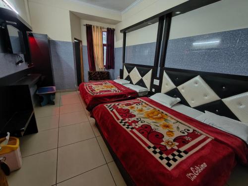 two beds in a hotel room with red sheets at AASHIRWAD HOTEL in Katra
