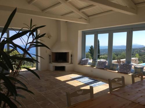 ein Wohnzimmer mit einem Sofa, einem TV und Fenstern in der Unterkunft Villa Xyloporta in Skinária