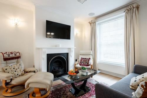 a living room with a fireplace and a tv at Luxury 3BRs house in the heart of Victoria in London