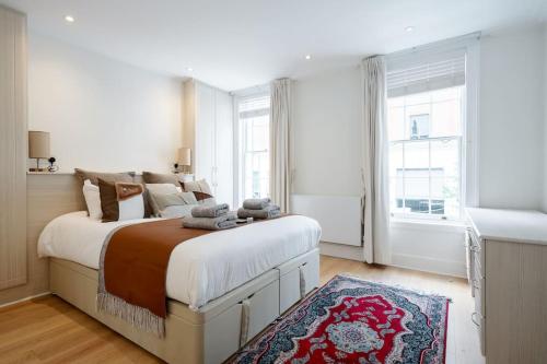 een witte slaapkamer met een groot bed en een raam bij Luxury 3BRs house in the heart of Victoria in Londen