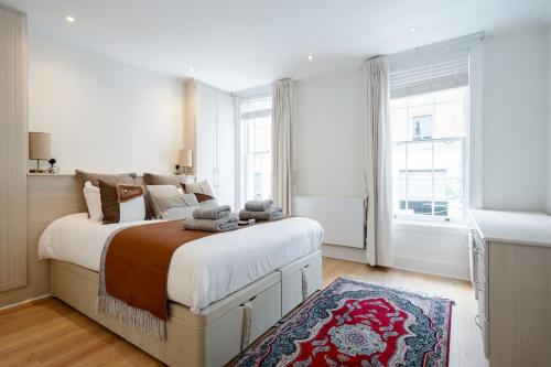 a white bedroom with a large bed and a window at Luxury 3BRs house in the heart of Victoria in London