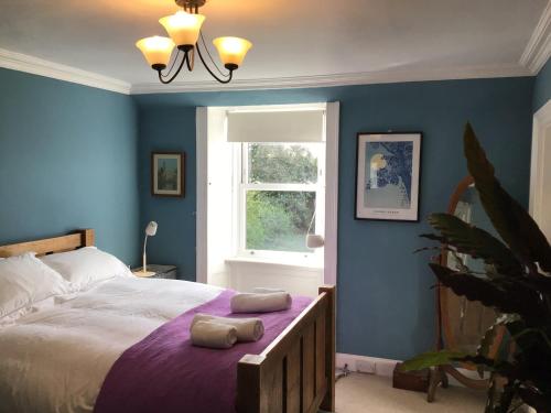 um quarto com uma cama com paredes azuis e uma janela em Mansefield Rooms em Lockerbie