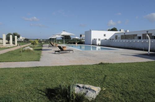 a swimming pool with benches next to a building at Masseria Giovanni in Martano