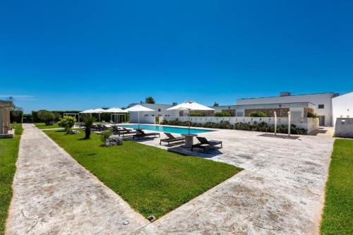 un patio trasero con piscina, mesas de picnic y sombrillas en Masseria Giovanni, en Martano