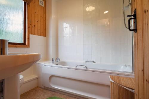 a white bathroom with a tub and a sink at Yew Tree Lodge in Minehead